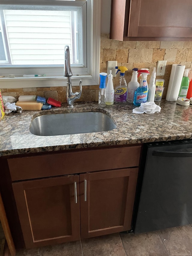 kitchen featuring stainless steel dishwasher, dark stone countertops, decorative backsplash, and sink