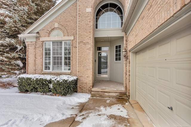 snow covered property entrance featuring a garage