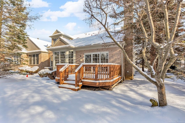 snow covered rear of property with a deck