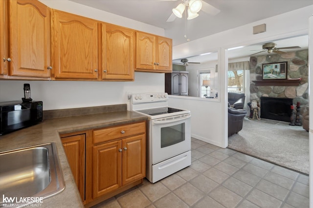 kitchen featuring sink, a stone fireplace, ceiling fan, electric range, and light colored carpet