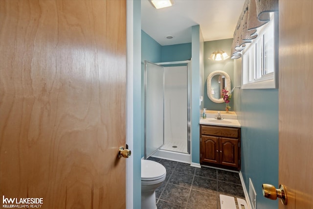 bathroom with toilet, vanity, and a shower with shower door