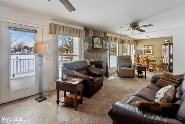 living room with ceiling fan with notable chandelier and a fireplace