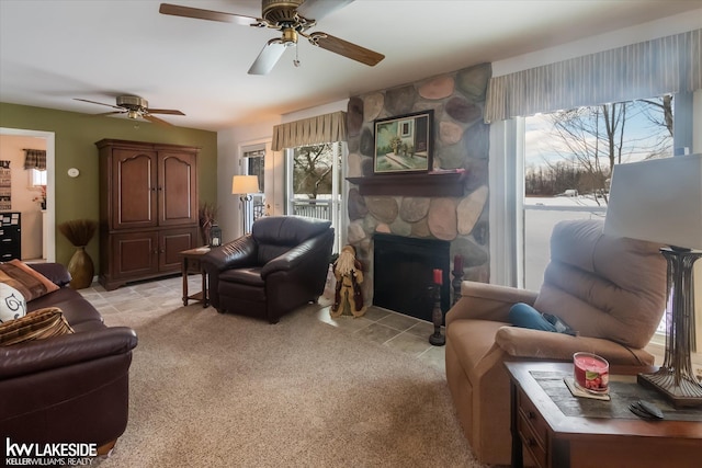 carpeted living room featuring a fireplace and ceiling fan