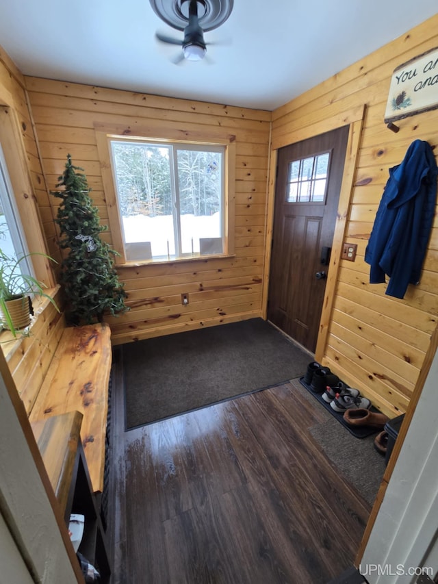 foyer with dark hardwood / wood-style flooring, wood walls, and ceiling fan