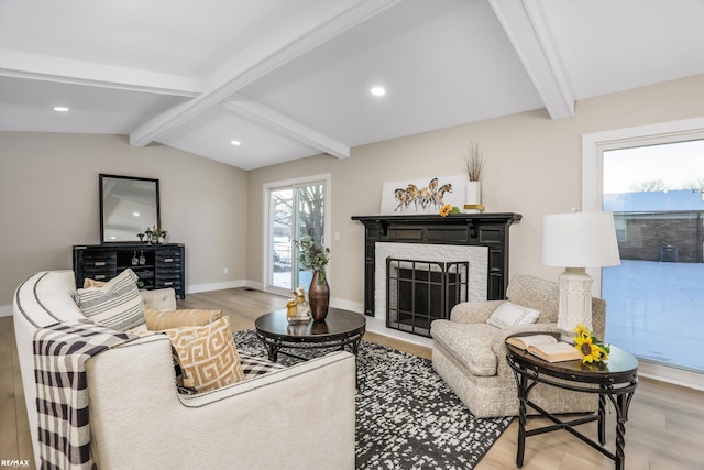 living room featuring hardwood / wood-style flooring, vaulted ceiling with beams, and a stone fireplace