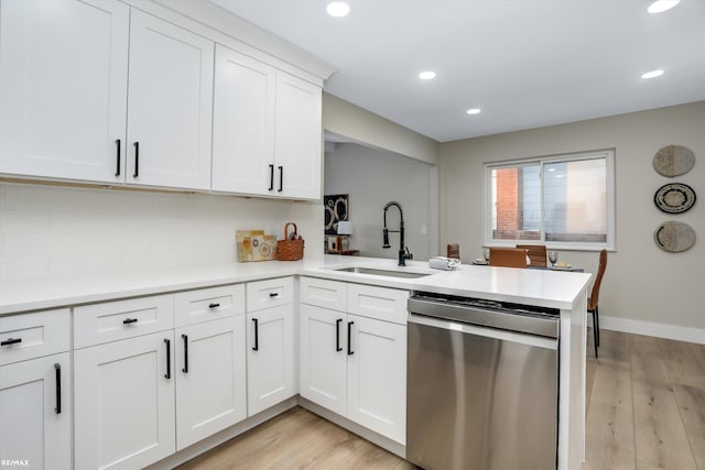 kitchen featuring stainless steel dishwasher, white cabinetry, sink, and kitchen peninsula