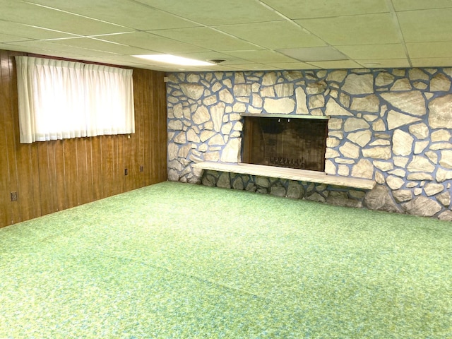 interior space featuring a drop ceiling, carpet, and a stone fireplace