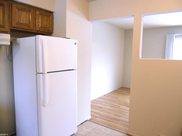 kitchen with white refrigerator, extractor fan, and light tile patterned flooring