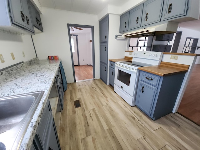 kitchen with light wood-type flooring, blue cabinets, electric range, and sink