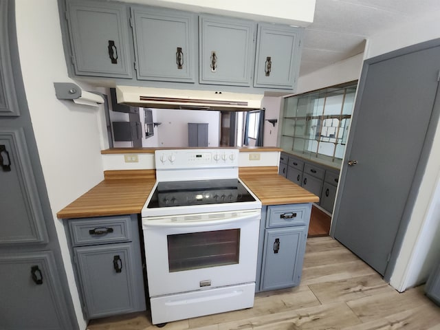 kitchen with exhaust hood, white range with electric stovetop, butcher block counters, and light hardwood / wood-style flooring