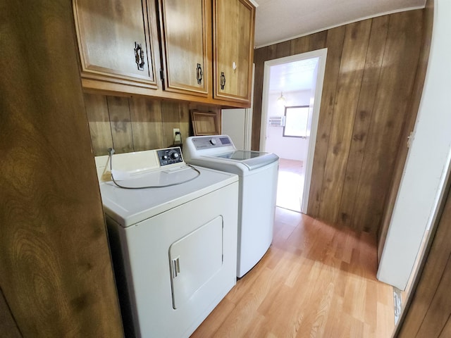 laundry area with cabinets, separate washer and dryer, light hardwood / wood-style floors, and wood walls