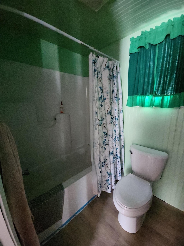 bathroom with toilet, shower / tub combo with curtain, and hardwood / wood-style flooring