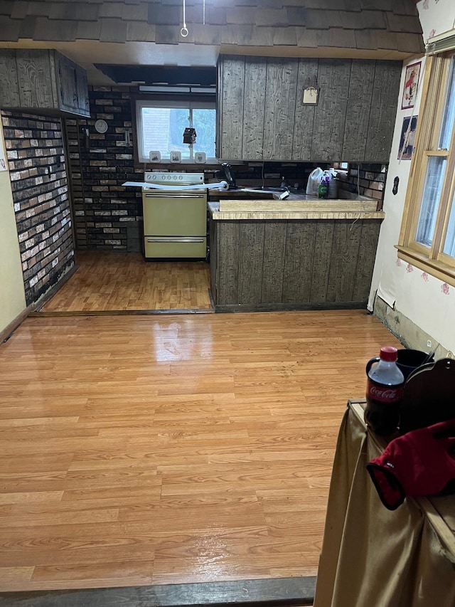 kitchen featuring range, brick wall, wood walls, and light hardwood / wood-style floors