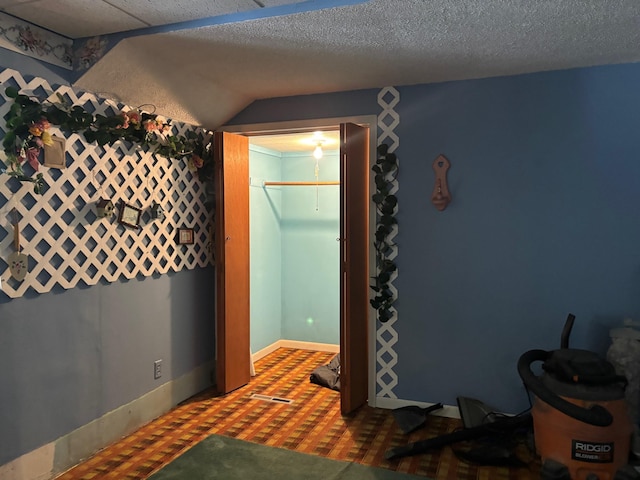 bedroom with vaulted ceiling, a textured ceiling, and a closet