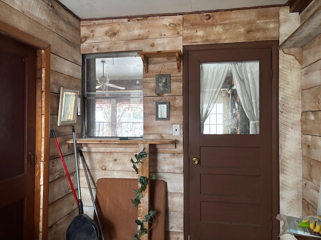 entrance foyer featuring wooden walls, ceiling fan, and plenty of natural light