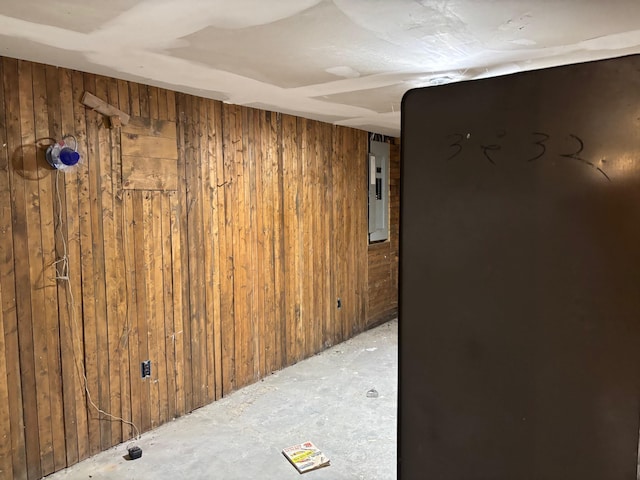 basement featuring wood walls and electric panel