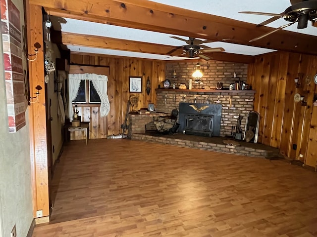 unfurnished living room with ceiling fan, light wood-type flooring, wood walls, and a wood stove