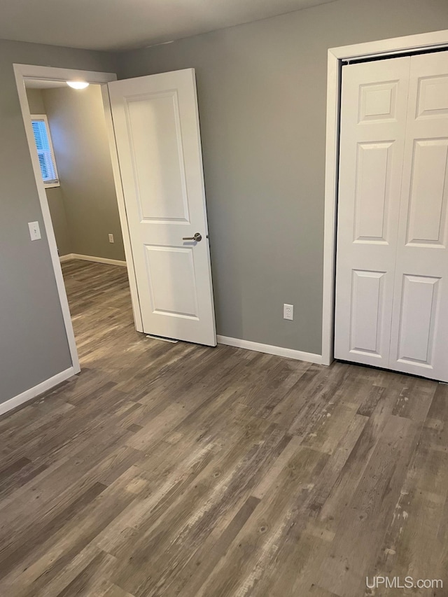 unfurnished bedroom with a closet and dark hardwood / wood-style floors