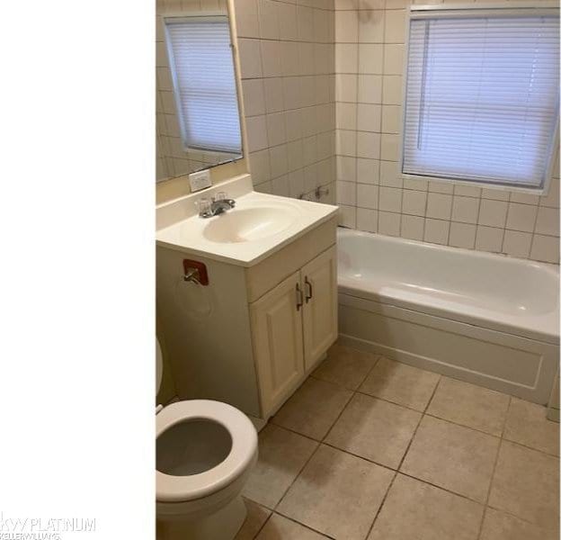 full bathroom featuring toilet, vanity, tile patterned floors, and tiled shower / bath combo