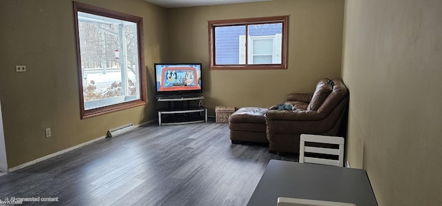 living area featuring a baseboard radiator, a healthy amount of sunlight, and dark wood-type flooring