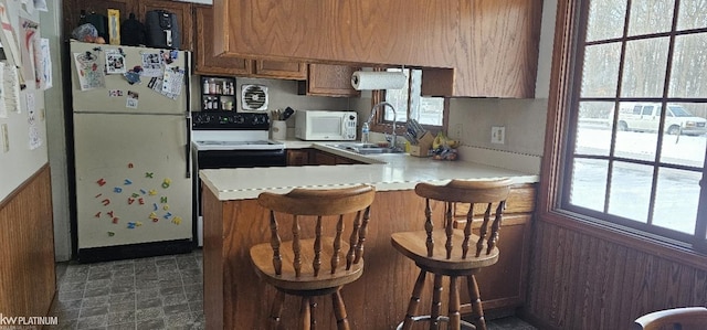 kitchen featuring white appliances, a kitchen breakfast bar, sink, and kitchen peninsula