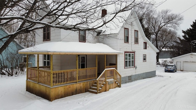 view of front of house featuring a garage, covered porch, and an outbuilding