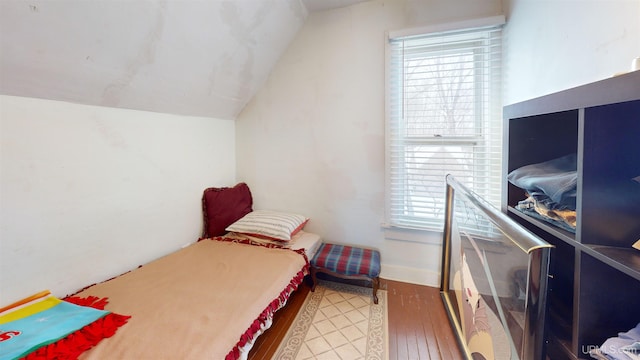 bedroom featuring lofted ceiling, wood-type flooring, and multiple windows