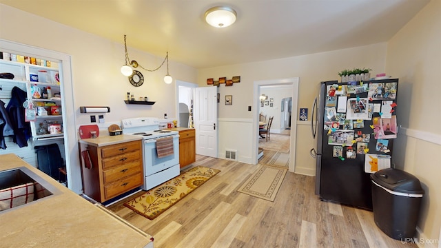 kitchen featuring white range with electric cooktop, pendant lighting, light wood-type flooring, and stainless steel fridge