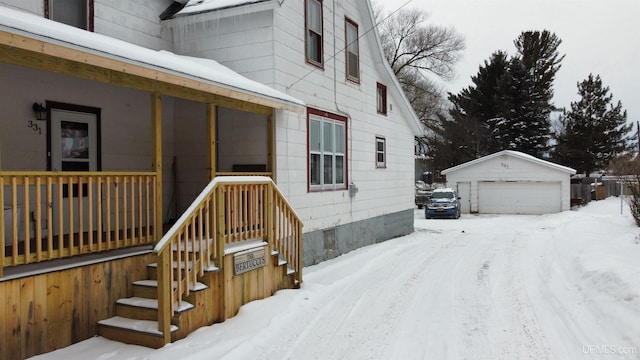 view of snowy exterior featuring a garage and an outbuilding