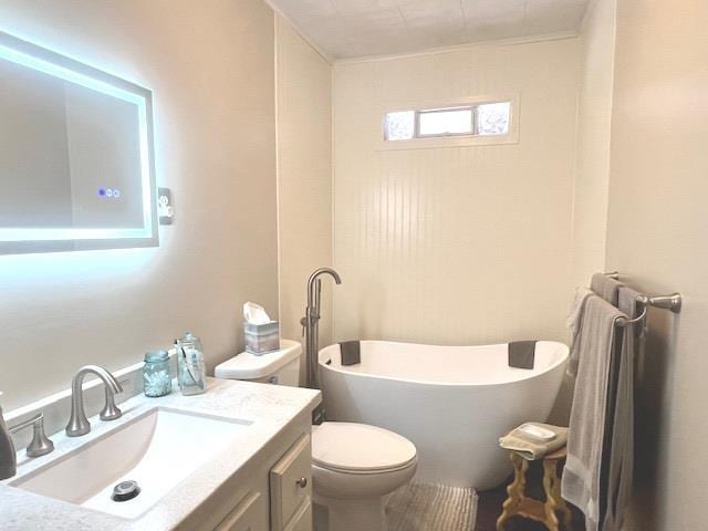 bathroom with toilet, a washtub, and vanity