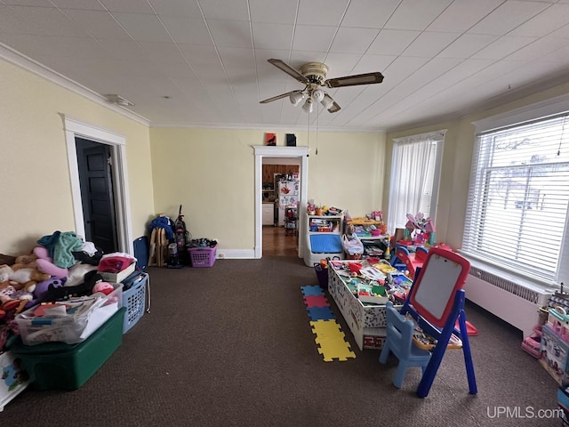 recreation room with a healthy amount of sunlight, ceiling fan, ornamental molding, and radiator heating unit