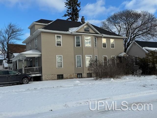 snow covered property with covered porch