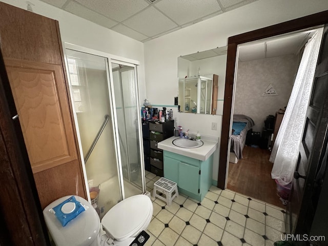 bathroom with toilet, vanity, a drop ceiling, and a shower with shower door