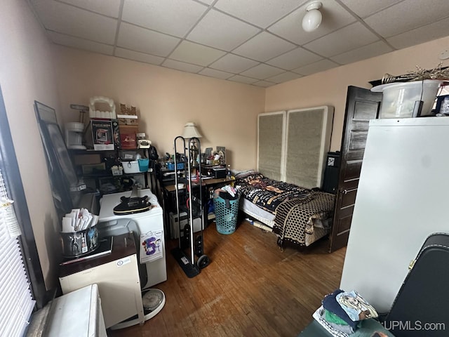 bedroom with washer / clothes dryer, hardwood / wood-style flooring, and white fridge