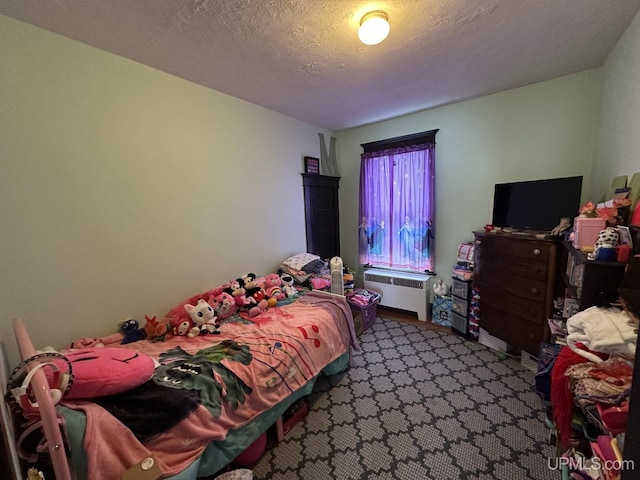 bedroom with a textured ceiling and radiator heating unit