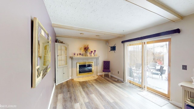 unfurnished living room with beam ceiling, light wood-type flooring, a textured ceiling, and a fireplace