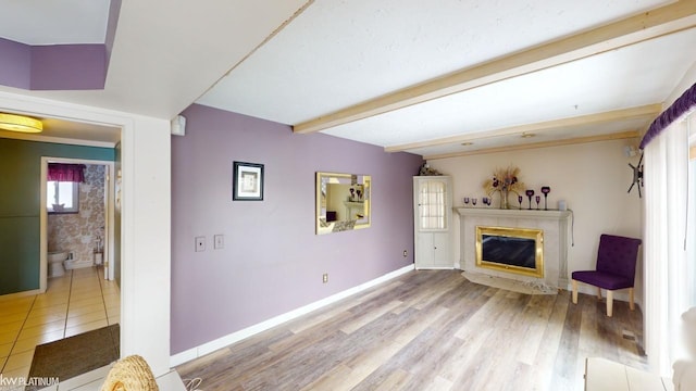 unfurnished living room featuring a high end fireplace, light hardwood / wood-style floors, and beamed ceiling