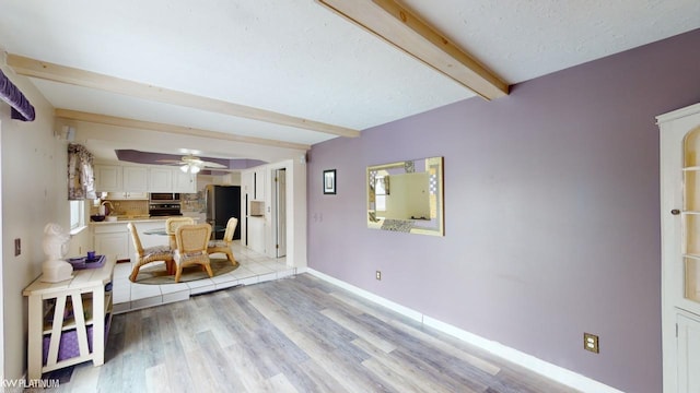 interior space featuring a textured ceiling, ceiling fan, beamed ceiling, and light hardwood / wood-style flooring