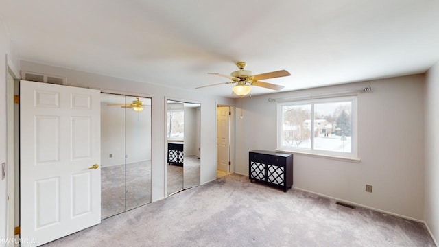 unfurnished bedroom featuring multiple closets, ceiling fan, and light colored carpet