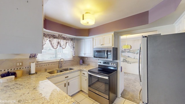 kitchen featuring stainless steel appliances, sink, white cabinetry, backsplash, and light stone countertops