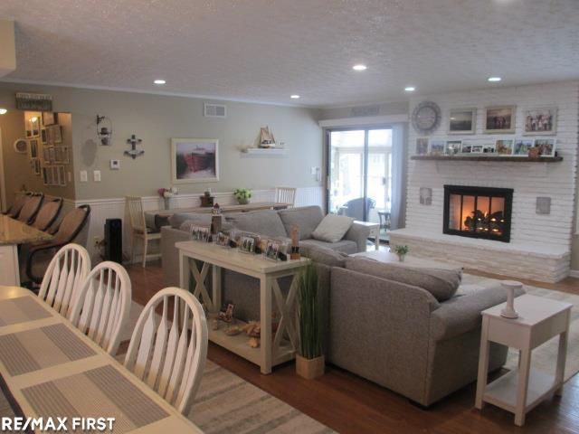 living room with dark hardwood / wood-style flooring, a brick fireplace, and a textured ceiling