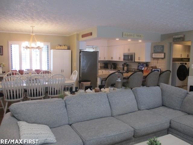 living room featuring washer / dryer, a textured ceiling, and a chandelier