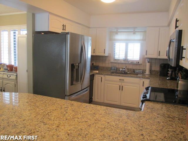 kitchen featuring appliances with stainless steel finishes, white cabinetry, backsplash, and sink