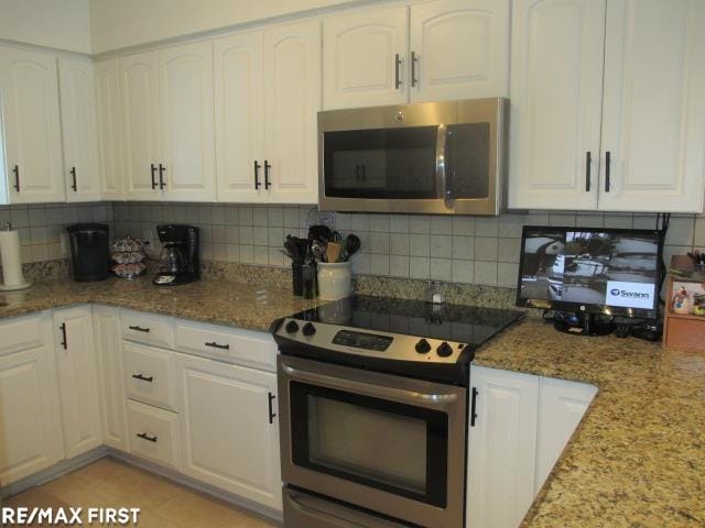 kitchen featuring appliances with stainless steel finishes, white cabinetry, stone counters, and tasteful backsplash