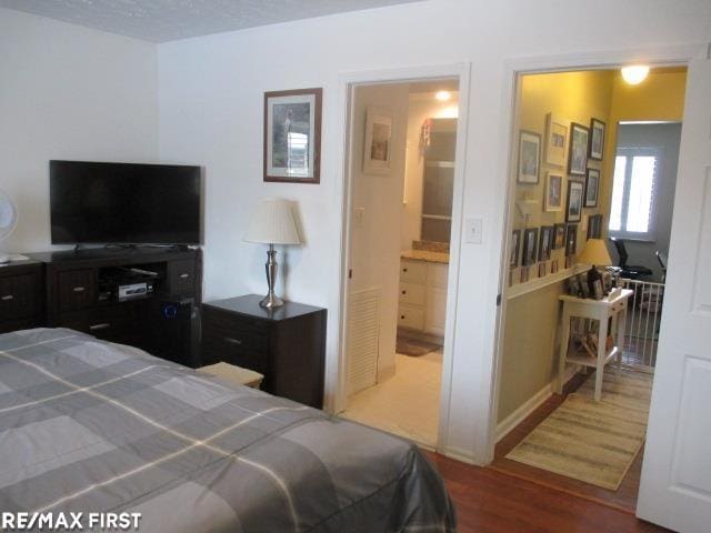 bedroom with ensuite bathroom and hardwood / wood-style flooring