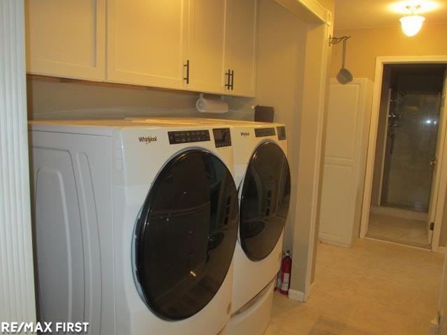 clothes washing area with separate washer and dryer and cabinets