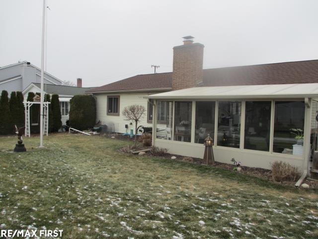 rear view of house featuring a yard and a sunroom