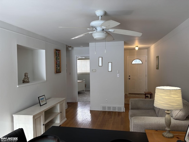 living room featuring ceiling fan and dark hardwood / wood-style floors