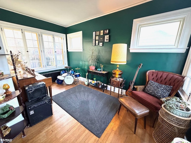 living area featuring crown molding, wood-type flooring, and radiator heating unit