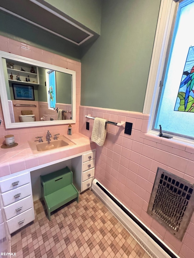 bathroom with toilet, tile walls, a baseboard heating unit, tile patterned floors, and vanity